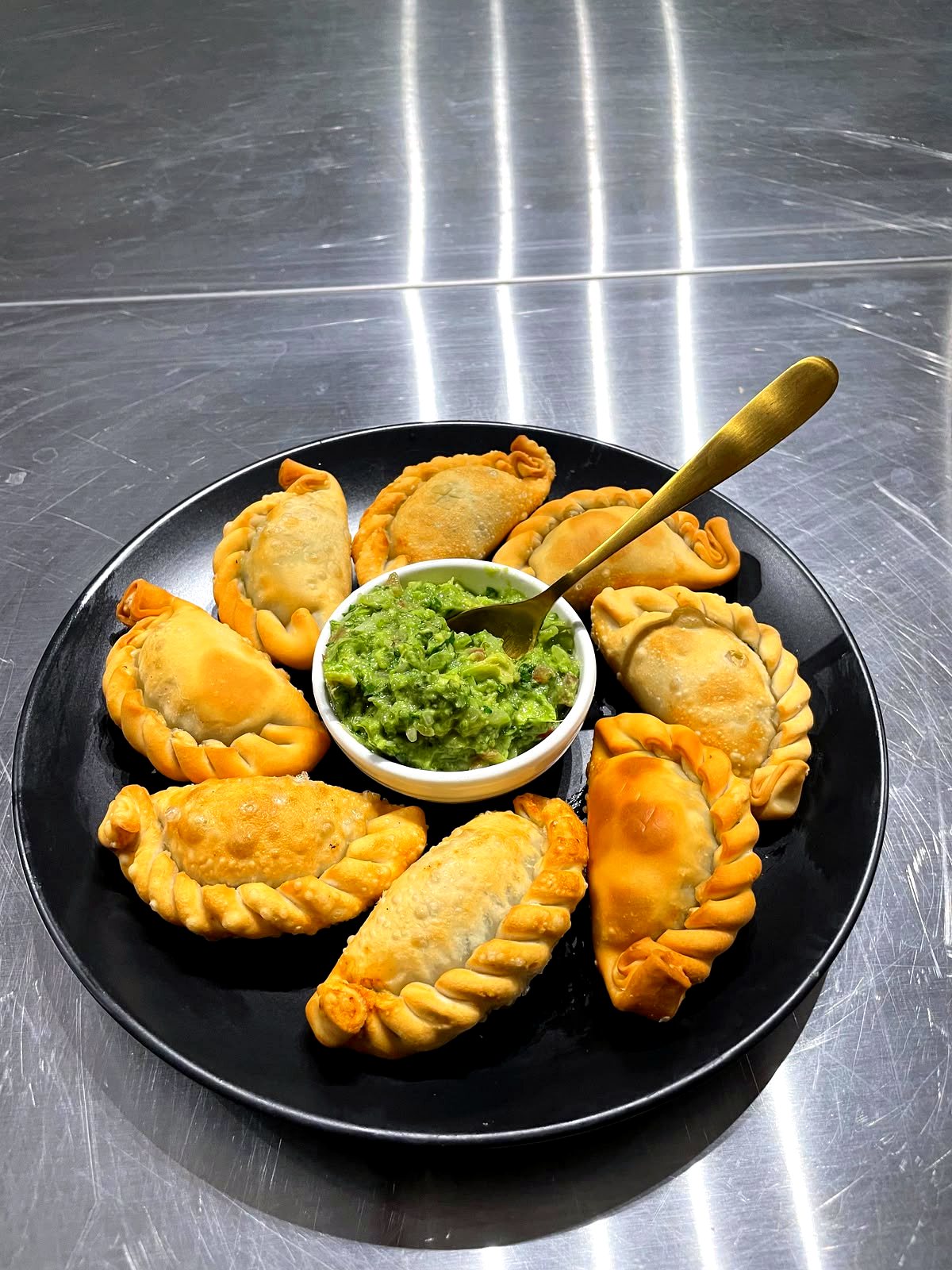 Plato de empanadas fritas con salsa verde de palta